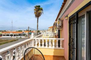 a balcony with a chair and a palm tree at Encantadora casa vacacional en El Chaparral in Torrevieja