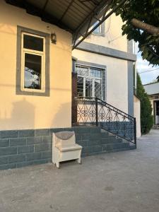 a chair sitting outside of a house with a window at Mama Gulya in Bishkek