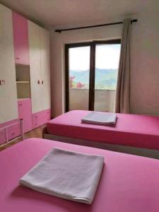 a pink room with two beds and a window at La VILLETTA in Masera
