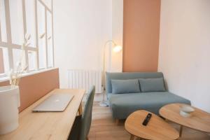 a living room with a table and a blue couch at Stadium Pink Loft 5min Rer near Paris in Aubervilliers