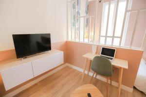 a bedroom with a desk with a television and a laptop at Stadium Pink Loft 5min Rer near Paris in Aubervilliers