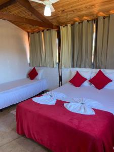 a bedroom with two beds with red and white pillows at Pousada sollaris in Serra do Cipo