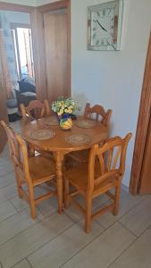 a wooden table with chairs and a clock on the wall at APARTAMENTOS ROSI - 5-10 Minute Walk To La Zenia Beach, Sea View, Beach Bar, Cliff Walk, Shops, Paddys Point, Cabo Roig - Free fast Fibre Optic Broadband, Free Parking, Tassimo coffee machine, TV Firestick compatible in Playas de Orihuela +16 photos