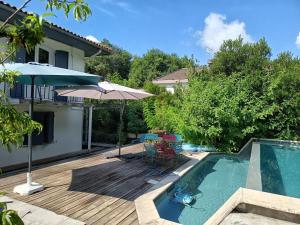 a deck with a pool and an umbrella next to a house at Chambre Zen Mérignac Aéroport Tram clim SDB priv in Mérignac