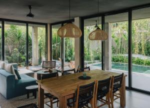 a living room with a wooden table and chairs at Aloha Villas - Modern villas with private pool and lush gardens in Kuta Lombok