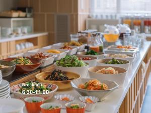 a buffet line with bowls of food on it at Mitsui Garden Hotel Kyoto Shijo in Kyoto