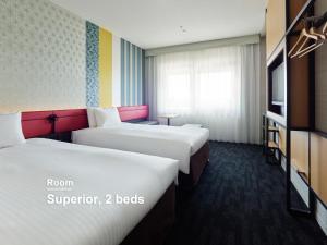 two beds in a hotel room with two beds at Mitsui Garden Hotel Kyoto Shijo in Kyoto