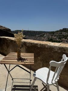 Una mesa de madera y una silla blanca en un balcón. en La grotta Mutycense, en Módica 7 fotos más