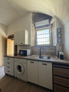 una cocina con fregadero y lavadora en La grotta Mutycense, en Módica