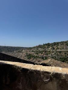 a view from the top of a stone wall with a mountain at La grotta Mutycense in Modica +7 photos