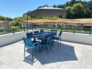 a table and chairs with an umbrella on a patio at Écrin Neuf au Cœur du Golf in Saint-André-des-Eaux