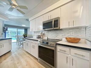 a kitchen with white cabinets and a stove top oven at Siesta Key Paradise, Vacation Pool Home, Near Beach, Restaurants and More in Sarasota