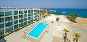 an overhead view of a hotel with a swimming pool and the ocean at Too Coool 1 Bedroom Apartment Coralli Resort in Protaras