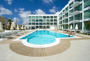 a swimming pool in front of a large building at Too Coool 1 Bedroom Apartment Coralli Resort in Protaras