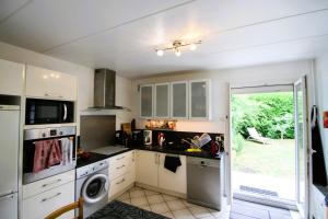 a kitchen with white cabinets and a washer and dryer at Le Jardin Champenois Maison in Tinqueux
