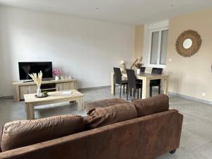 a living room with a brown couch and a table at Ô Coeur des Champs in Réty