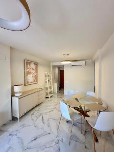 a dining room with a glass table and white chairs at Playa Sol 2 in Denia