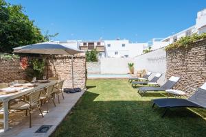 Un patio con sillas y mesas y una sombrilla. en Al Sur Home Marqués, en Sevilla