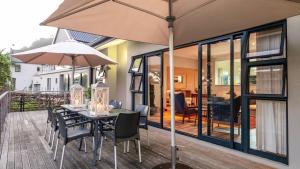 Una mesa y sillas con una sombrilla en un patio. en Waterside Holiday House, en Wilderness