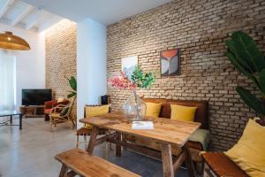 Una mesa de madera con un jarrón de flores encima. en Al Sur Home Marqués, en Sevilla