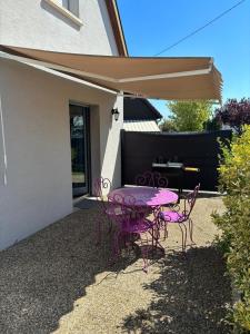 ein rosa Tisch und Stühle unter einem Sonnenschirm in der Unterkunft Chez Tony in Wintzenheim