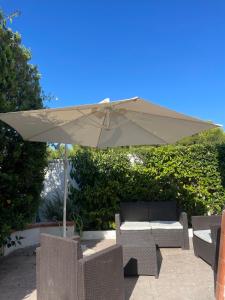 a tan umbrella and chairs and a couch under it at Villa Raffa Salento in Maruggio