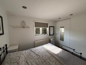 a bedroom with a bed and a window at Mooi chalet op de Veluwe! in Lunteren