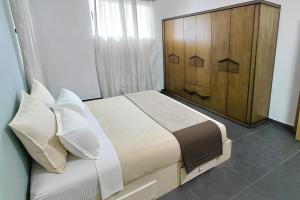 un letto con cuscini bianchi e testiera in legno di Pointe aux Piments Residence a Pointe-aux-Piments