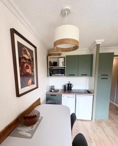 una cucina con tavolo bianco in una camera di Pierre et Vacances Les Bergers au Pied des pistes & Piscine -Sauna & Balcon Sud a LʼAlpe-dʼHuez Altre 47 foto