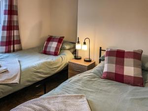 ein Schlafzimmer mit 2 Betten und einer Lampe auf einem Tisch in der Unterkunft Trinity Cottage in Abergavenny
