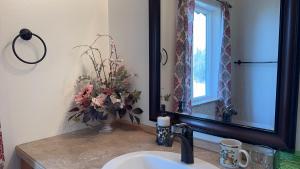 a bathroom sink with a vase of flowers next to a mirror at Majestic View Roundhouse - Relax Room in Wasilla