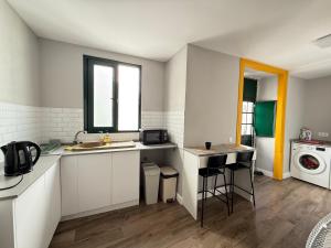 a kitchen with white cabinets and a sink and a window at Faro Coast Guest House in Faro