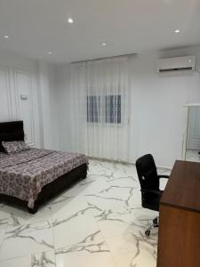 une chambre avec un lit, un bureau et une chaise dans l'établissement AL MIDIAF STYLISH VILLA &Garage, à Mostaganem