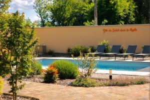 a swimming pool in a garden with chairs around it at Gîte du Soleil dans la Ruelle - Les Hirondelles in Yvré-lʼÉvêque