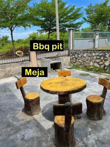 a wooden table and two stump stools in a park at Almai Homestay Batu 4 in Port Dickson +2 photos
