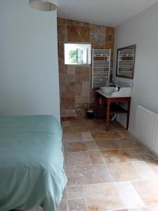 a bedroom with a bathroom with a sink and a bed at La petite Maison du Manoir de La Grande Vigne in Mayenne
