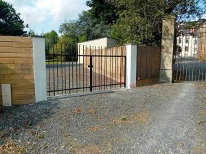 an open gate with a wooden fence at La petite Maison du Manoir de La Grande Vigne in Mayenne +1 photo