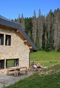 a woman sitting on a picnic table next to a building at La loge de la Dolarde in Prémanon