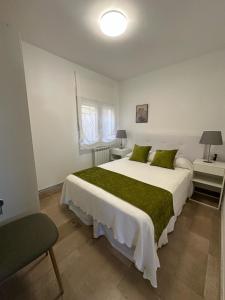 a bedroom with a large white bed with green pillows at Chancelas A in Combarro
