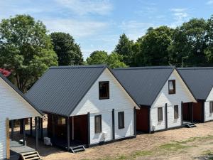 a row of white barns with black roofs at Amber Coast - Domek nr 1 i 3 in Jantar