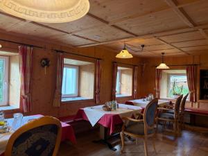 a dining room with tables and chairs and windows at Pension Wirt am Bach in Terento +8 photos