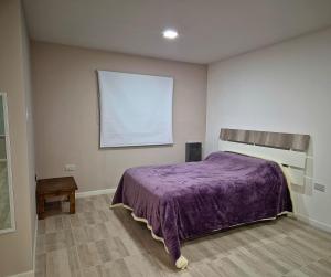 a bedroom with a bed with a purple blanket at Puesta del Sol Apart in Río Gallegos