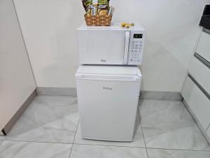 a microwave sitting on top of a refrigerator at Flat completo 1 minuto da feira quartas e domingos in Aparecida de Goiania