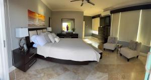 ein Schlafzimmer mit einem großen Bett und einem Stuhl in der Unterkunft Palapa House in Tijuana