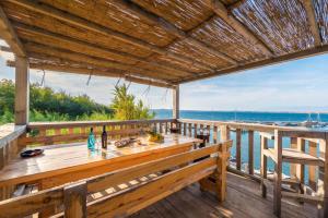 a wooden deck with a table and a view of the ocean at Apartments Delfin with seaview 100 meters from the sea - by TA Leut Agency in Privlaka