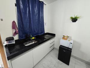 a small kitchen with a sink and a microwave at Flat completo 2 minutos da feira domingo e quarta in Aparecida de Goiania