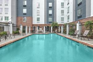 ザ・ウッドランズにあるCandlewood Suites Houston The Woodlands by IHGの椅子と建物のあるプール