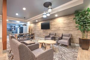 ザ・ウッドランズにあるCandlewood Suites Houston The Woodlands by IHGのレンガの壁にテレビと椅子が備わるロビー