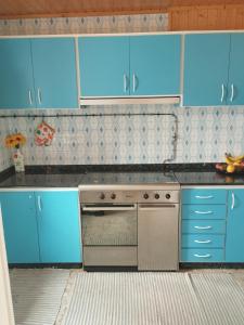 kuchnia z niebieskimi szafkami i kuchenką w obiekcie Camino Bed and Breakfast Corme w mieście Corme-Puerto