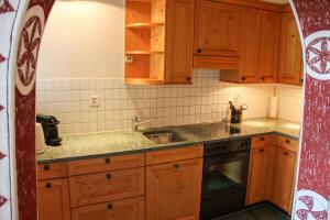 a kitchen with wooden cabinets and a sink at Wohnung Steinbock Savognin in Savognin